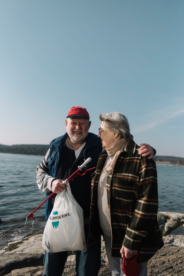 Ett äldre par plockar skräp vid vattnet