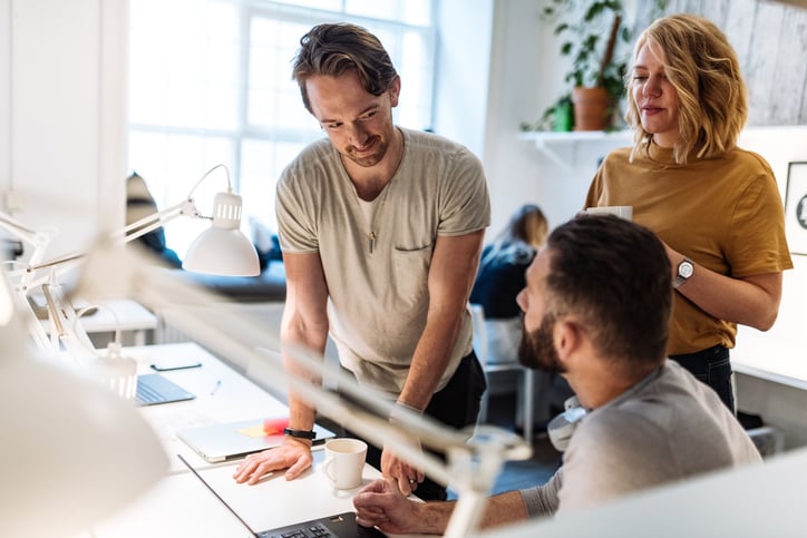 Kollegor runt ett skrivbord som pratar